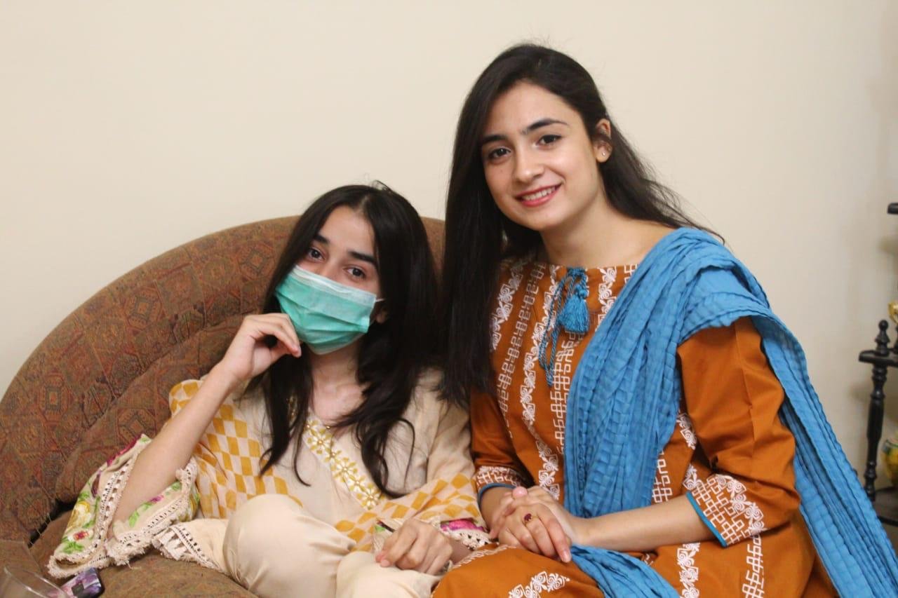 Two people seated together, one wearing a blue scarf